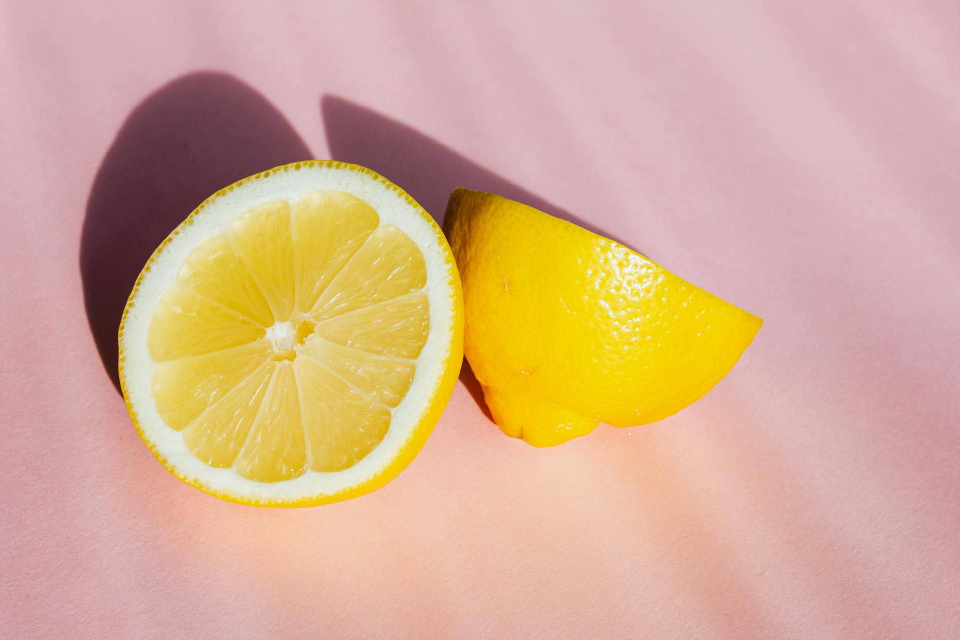 Halves of fresh lemon on a pink background, symbolizing renewal and gentle healing