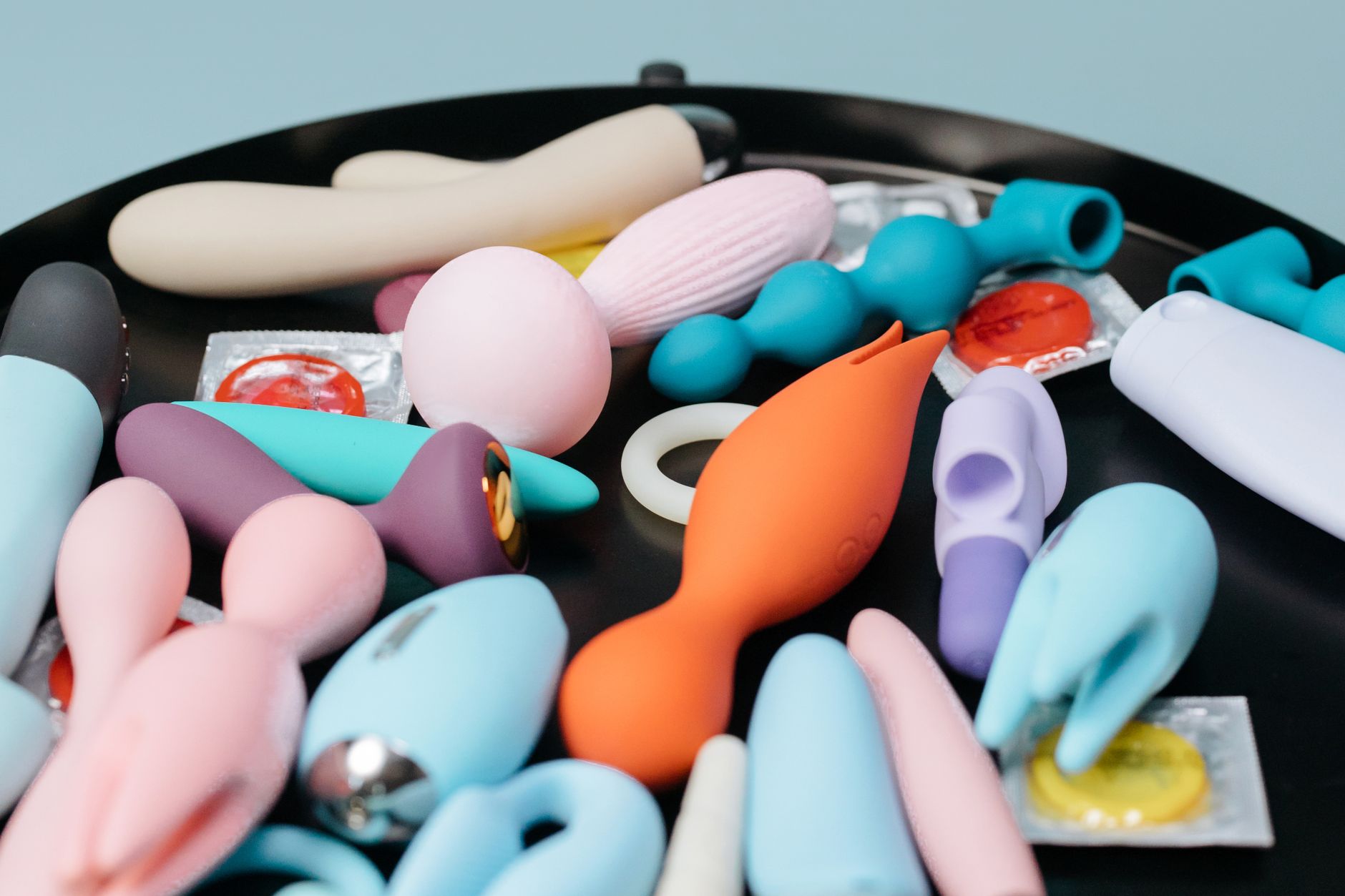 A collection of colorful clitoral vibrators and intimate wellness devices on a black surface.
