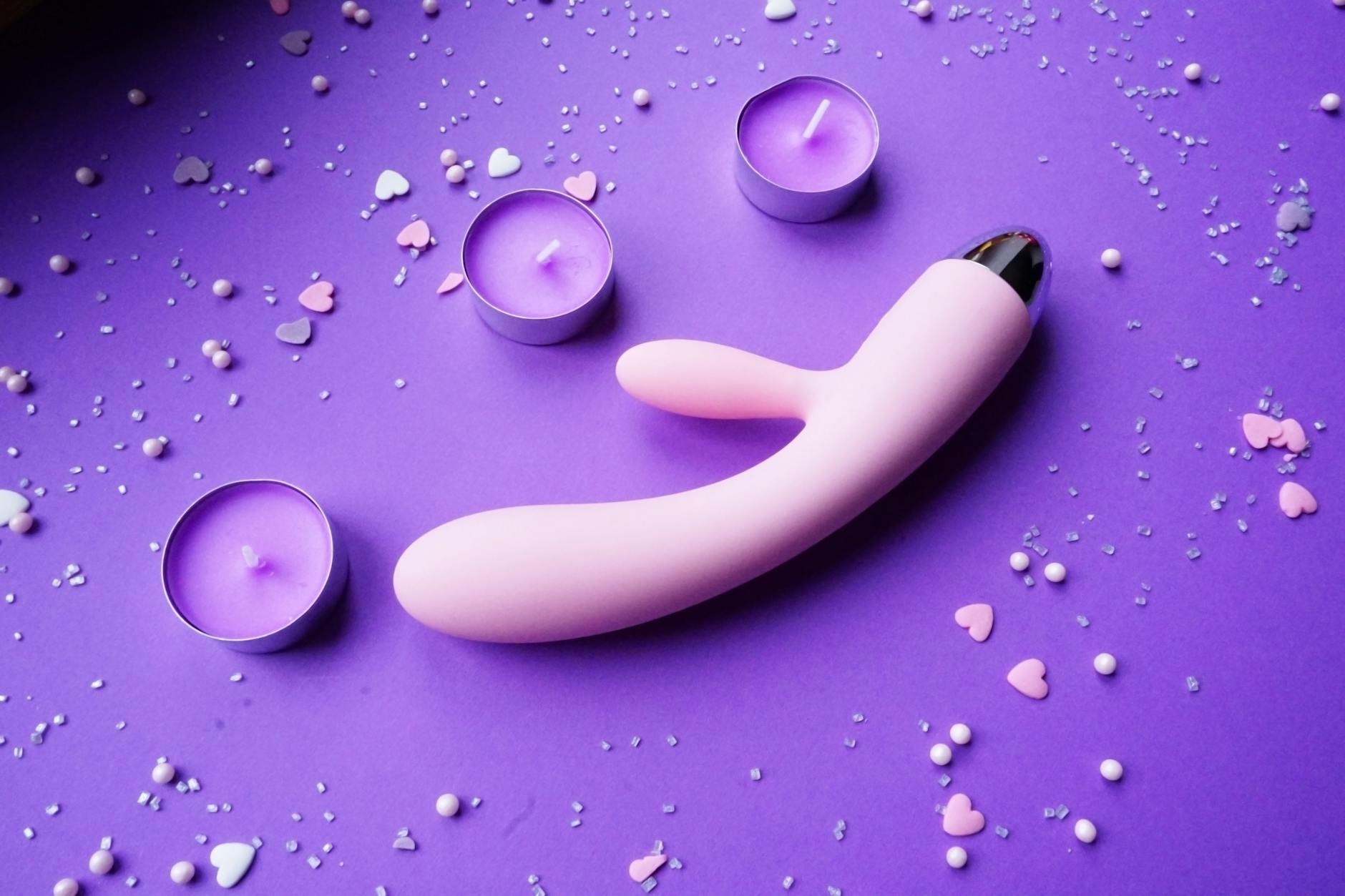 Lemon vibrator on purple background with romantic lighting and candles